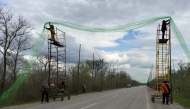 Ukrainian servicemen cover the road with a net to protect vehicles from drone attacks at an undisclosed location in the Zaporizhzhia region on April 10, 2026. (Photo by Darya Nazarova / AFP)