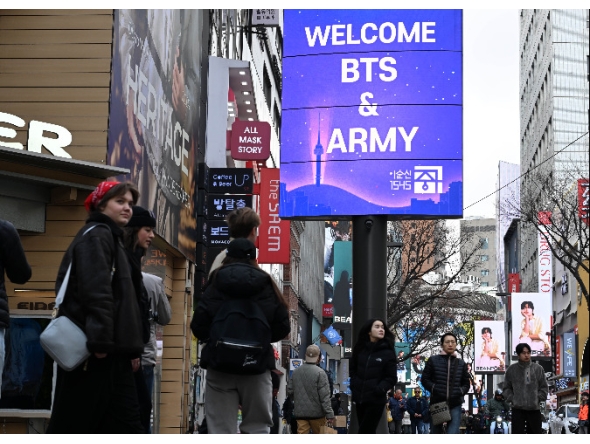Tourists walk past a “Welcome BTS” sign in Myeong-dong, central Seoul, on Friday, a day ahead of the group’s comeback concert. (Lee Sang-sub/The Korea Herald)