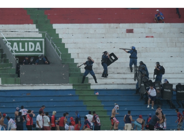Fans of Cerro Porteno clash with police officers during the Paraguayan tournament football match between Olimpia and Cerro Porteno at the Defensores del Chaco stadium in Asuncion on April 19, 2026. (Photo by Daniel Duarte / AFP)