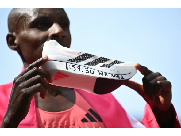 Kenya's Sabastian Sawe poses with his new world record time written on his running shoe at the finish of the 2026 London Marathon in central London on April 26, 2026. (Photo by JUSTIN TALLIS / AFP) / “Restricted to editorial use - sponsorship of content subject to LMEL agreement”.