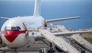 A Spanish evacuee wearing a white hazmat protective suit boards the rear door of a Spanish air force Airbus A310 plane at the Tenerife Sur-Reina Sofia airport after being evacuated from the Dutch flagged hantavirus-stricken cruise ship MV Hondius which anchored at the industrial port of Granadilla de Abona on the island of Tenerife in Spain's Canary Islands on May 10, 2026. Photo by Antonio Sempere / AFP
