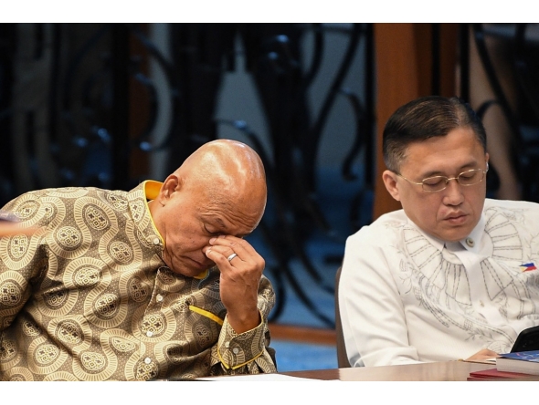 Philippine Senator Ronald dela Rosa (L) gestures next to colleague Christopher Go during a Senate plenary session on the third day of him holed up in the Senate building in Manila on May 13, 2026. Photo by TED ALJIBE / AFP