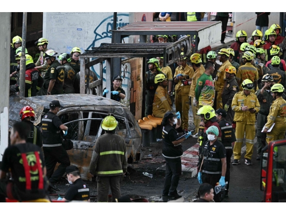 Forensic police officers, rescue workers and firefighters stand at the site of a train collision with a bus underneath Makkasan Airport Rail station in Bangkok on May 16, 2026. (Photo by Lillian SUWANRUMPHA / AFP)