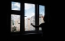 A local resident removes glass shards from a broken window in a residential building following an air attack in Krasnogorsk, Moscow region on May 17, 2026. (Photo by Tatyana Makeyeva / AFP)