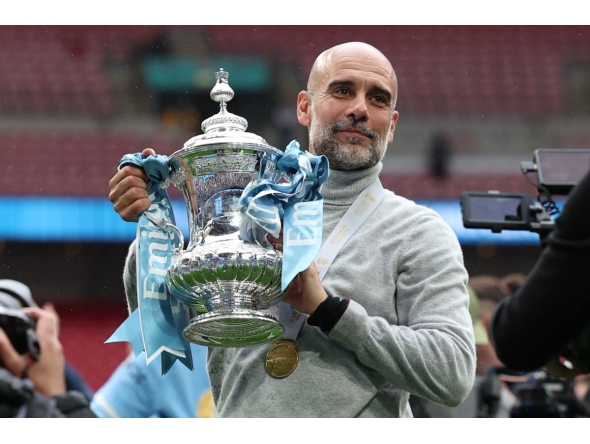 Manchester City's Spanish manager Pep Guardiola poses with the trophy on the pitch after the English FA Cup final football match between Chelsea and Manchester City at Wembley stadium in London, on May 16, 2026. Photo by ADRIAN DENNIS / AFP