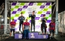 The podium winners of the third round pose with officials. 