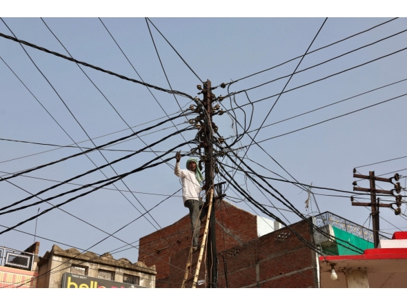 A worker repairs a street light in Varanasi on May 22, 2026. (Photo by Niharika KULKARNI / AFP)