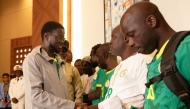President of Senegal Bassirou Diomaye Faye (L) shakes hands with Senegalese supporters who were granted a royal pardon in Morocco as they arrive at Blaise Diagne International Airport in Ndiass, Senegal (Photo by Seyllou / AFP)