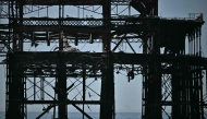 A paddleboarder is seen between the stanchions of the derelict West Pier off the beach in Brighton, on the south coast of England on May 25, 2026, as Monday is expected to be the hottest bank holiday.(Photo by Ben Stansaal / AFP)
 
