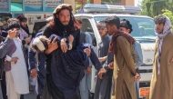 A man carries an injured girl to a hospital for treatment after a truck carrying Afghan families overturned in Jalalabad on May 30, 2026. (Photo by Aimal Zahir / AFP)