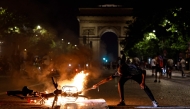 A member of the public holds an object to a burning bicycle on the Avenue de la Grande Armee during gatherings after PSG won the UEFA Champions League final between Paris Saint-Germain (PSG) and Arsenal FC played in Budapest (Photo by Kenzo Tribouillard / AFP)