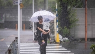 A woman holding her child walks through heavy rain brought by severe tropical storm Jangmi in Tokyo on June 3, 2026. (Photo by Yuichi Yamazaki / AFP)