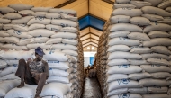 (Files) A worker sits atop sacks of food aid in a hangar at a World Food Programme (WFP) warehouse in Bor, Jonglei State, on February 13, 2026. (Photo by Luis Tato / AFP)
 