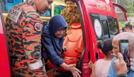 This handout photo taken and released by Perak's Fire and Rescue Department on June 6, 2026, shows rescuers assisting Jaslinda Saludin (2nd L) after she was found in a forested area in central Malaysia's Perak state. (Photo by Handout / Perak's Fire and Rescue Department / AFP)