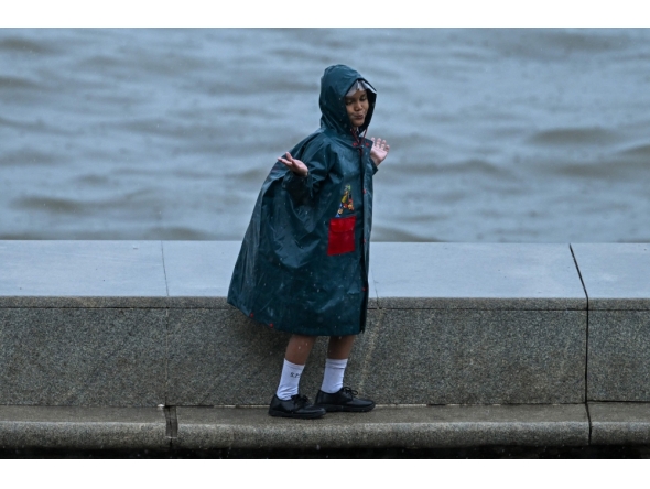 A child enjoys during rainfall while going to school, in Mumbai on June 23, 2026. (Photo by Punit Paranjpe/ AFP)
