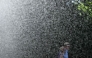 A man and woman walk past the water stream of a sprinkler system at the WTA 500 Bad Homburg Open tennis tournament in Bad Homburg, western Germany on June 25, 2026. (Photo by Kirill KUDRYAVTSEV / AFP)
 