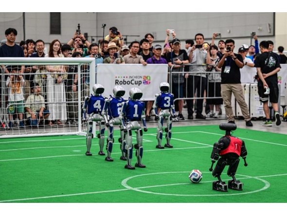 Spectators watch robots taking part in a football match at RoboCup 2026, a robotics and Artificial Intelligence (AI) competition in Incheon on July 3, 2026. (Photo by Jade Gao / AFP)