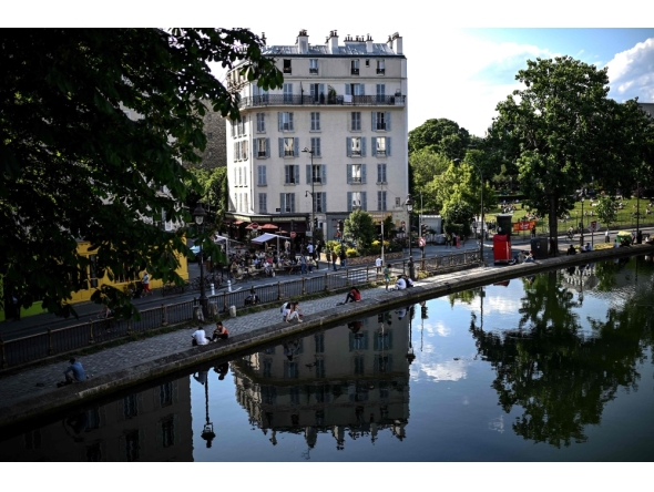Files: People sit along the canal Saint-Martin in Paris on May 17, 2022. Photo by Christophe Archambault / AFP