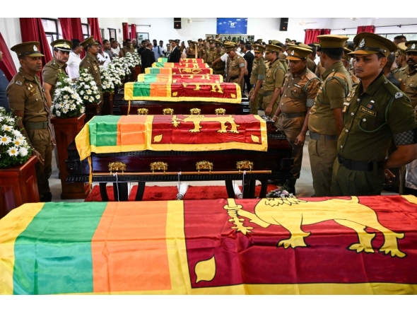 Security personnel pay tribute as they stand next to coffins of seven guards killed during Negombo prison riot in Colombo July 8, 2026. (Photo by Ishara S. Kodikara / AFP)