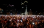 Spain's supporters turn on their phone flashlight as they watch the 2026 World Cup final match between Spain and Argentina displayed on giant screens underneath the Christopher Columbus statue on Colon square's in Madrid, on July 19, 2026. (Photo by Paul Hanna / AFP)