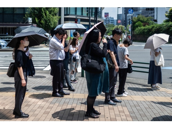 People carry umbrellas to shelter from the sun in Tokyo on July 23, 2026. (Photo by Andrew Caballero-Reynolds/ AFP)
 