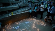Relatives light candles during a mass for the victims in Caraballeda, Venezuela, on July 24, 2026, one month after an earthquake struck the area. (Photo by Federico PARRA / AFP)