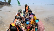 People sitting on a rescue boat ride through a flooded area after heavy monsoon rains induced a rise in the water level of the River Ravi in Muridke on July 27, 2026. (Photo by Arif ALI / AFP)