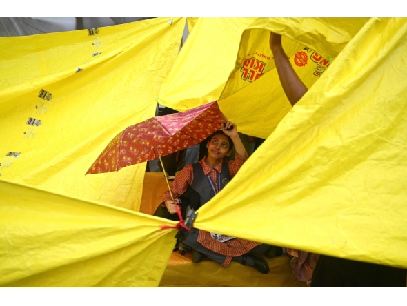 A school girl takes shelter under an umbrella at Jantar Mantar in New Delhi on July 24, 2026. (Photo by Arun Sankar / AFP)
 