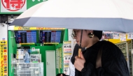 A woman walks past a display showing currency rates at a money exchange in Shinjuku district in Tokyo on July 24, 2026. Photo by ANDREW CABALLERO-REYNOLDS / AFP