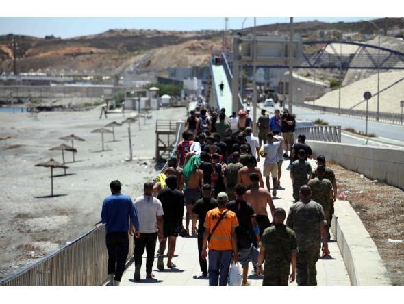 A group of migrants approach the border post to make their way back to Morocco, escorted by Spanish infantry soldiers, in the Spain's north African enclave of Ceuta, on August 2, 2026. (Photo by Henry Nicholls / AFP)