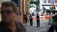 Police community support officers (PCSOs) speak to a person near cordon tape at Endell road in covent garden, central London on August 5, 2026. Photo by Henry NICHOLLS / AFP