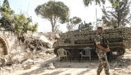 A Lebanese army soldier stands on guard by his armoured vehicle in the southern Lebanese village of Zawtar al-Gharbiyah which was previously badly damaged by the Israeli military on August 8, 2026. (Photo by Mahmoud ZAYYAT / AFP) /