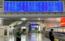 Passengers walk under a departure board at Ningbo railway station as most trains are cancelled due to approaching Typhoon Dolphin on August 9, 2026. (Photo by Rebecca BAILEY / AFP)