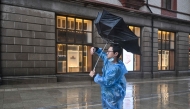 A man uses an umbrella to shelter from the rain on the Bund a day after Typhoon Dolphin made landfall in Shanghai on August 10, 2026. (Photo by Hector RETAMAL / AFP)