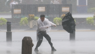 A man holds tightly onto an umbrella that is blown open by the wind amid rain at Huangpu District of Shanghai, east China, on Aug. 9, 2026. (Xinhua/Wang Xiang)