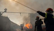 Firemen work to extinguish a fire that broke out at a livestock facility near Kouvaras, south of Athens, on August 10, 2026. (Photo by Aris MESSINIS / AFP)