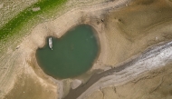 This aerial photograph shows the parched bed of Brenets Lake (Lac des Brenets), part of the Doubs River, a natural border between eastern France and western Switzerland, as central Europe is hit by a new heatwave, in Les Brenets on August 11, 2026. Photo by FABRICE COFFRINI / AFP