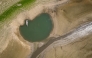 This aerial photograph shows the parched bed of Brenets Lake (Lac des Brenets), part of the Doubs River, a natural border between eastern France and western Switzerland, as central Europe is hit by a new heatwave, in Les Brenets on August 11, 2026. Photo by FABRICE COFFRINI / AFP