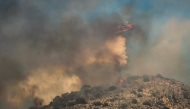 A firefighting helicopter drops water during a wildfire in the island of Salamina, near Athens, on August 16, 2026. (Photo by Yannis Panagopoulos / Eurokinissi / AFP)