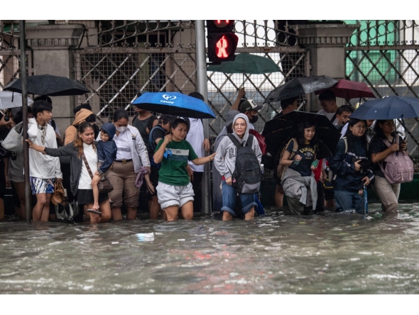 Commuters wade through a flooded street triggered by heavy monsoon rains in Manila on August 17, 2026. (Photo by Ted ALJIBE / AFP)

