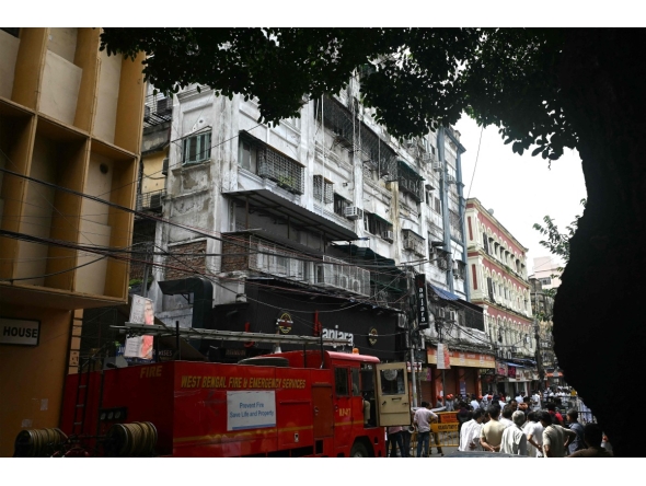 Onlookers and fire personnel gather at the site following a fire at a hotel in Kolkata on August 19, 2026. Photo by Dibyangshu SARKAR / AFP
