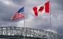 The US and Canadian flags flutter next to the Blue Water Bridge border crossing in Point Edward, Ontario, on October 24, 2025. (Photo by Geoff Robins / AFP)