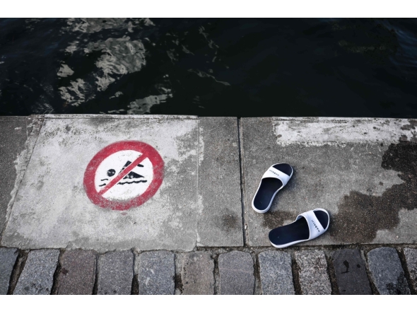 (FILES) This photograph shows sandals next to a sign indicating that swimming is forbidden, at the Bassin de la Villette during a cold water swimming event in Paris on March 29, 2025.(Photo by Thibaud MORITZ / AFP)