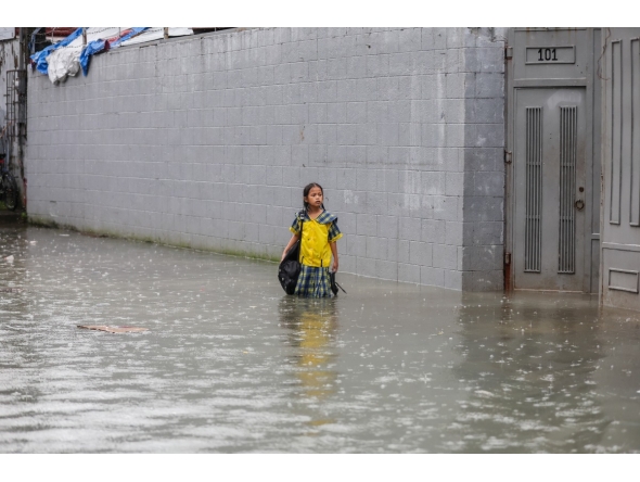 A student stands in floodwater in Quezon City, the Philippines, on Aug. 17, 2026. (Xinhua/Rouelle Umali)