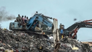 Residents and rescuers use an excavator to search for bodies after a landslide struck the Dar es Salaam dumpsite overnight in Conakry on August 23, 2026. (Photo by AFP)