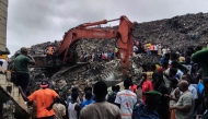 Residents and rescuers use an excavator to search for bodies after a landslide struck the Dar es Salaam dumpsite overnight in Conakry on August 23, 2026.