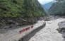 Fire and rescue personnel conduct search and rescue operations on a section of a road leading to Gyirong Port which was damaged after a mudslide two days earlier, in Gyirong County, in China's western Tibet region on August 28, 2026. (Photo by CNS / AFP)
