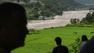 Residents look at the Trishuli River as they take shelter at an elevated place after a flood warning in the Pipaltar area of Nepal's Nuwakot district on August 28, 2026. (Photo by Arun SANKAR / AFP)
