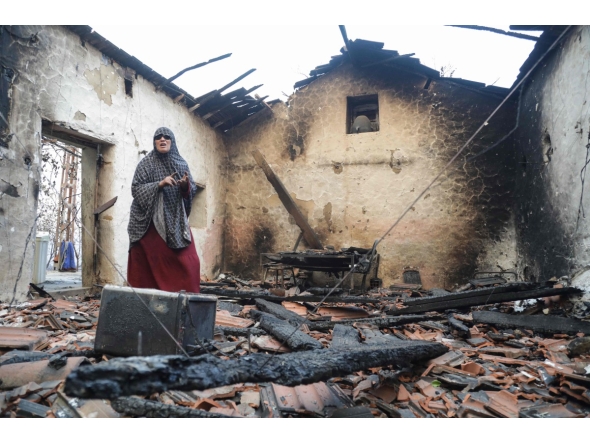 A woman inspects her damaged house after it was burned down in a forest fire in Bordj T'har, a town and commune in Algeria's northeastern Jijel Province, on August 27, 2026. (Photo by AFP)