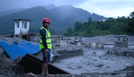 A disaster rescue personnel looks on at the site of damaged buildings in the aftermath of flash floods at Trishuli Bazar in Nepal's Nuwakot district on August 29, 2026. (Photo by MANAN VATSYAYANA / AFP)